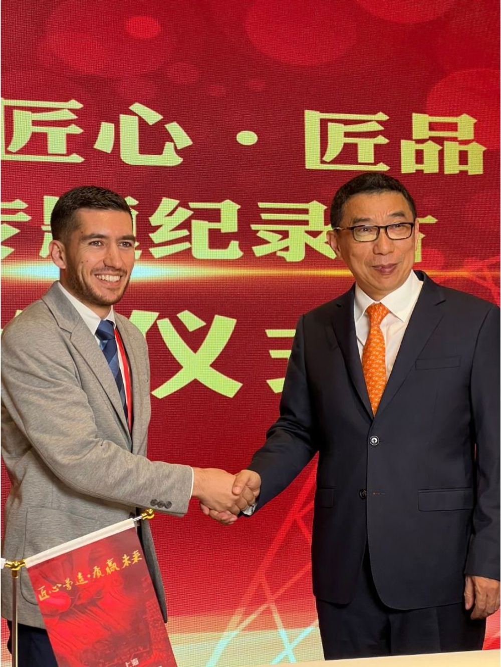 Syed Shawal serrant la main d'un représentant de CCTV China lors du Salon international du livre de Shanghai 2024