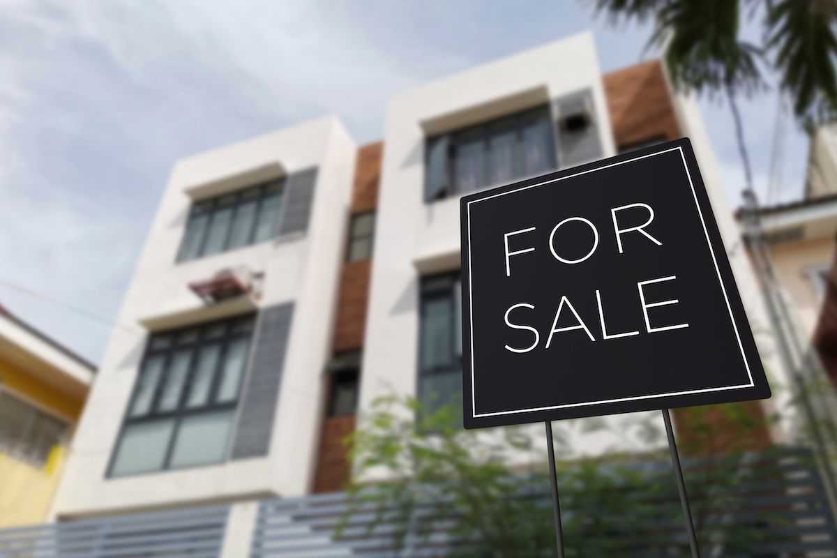 For sale sign in front of an affordable three story apartment building