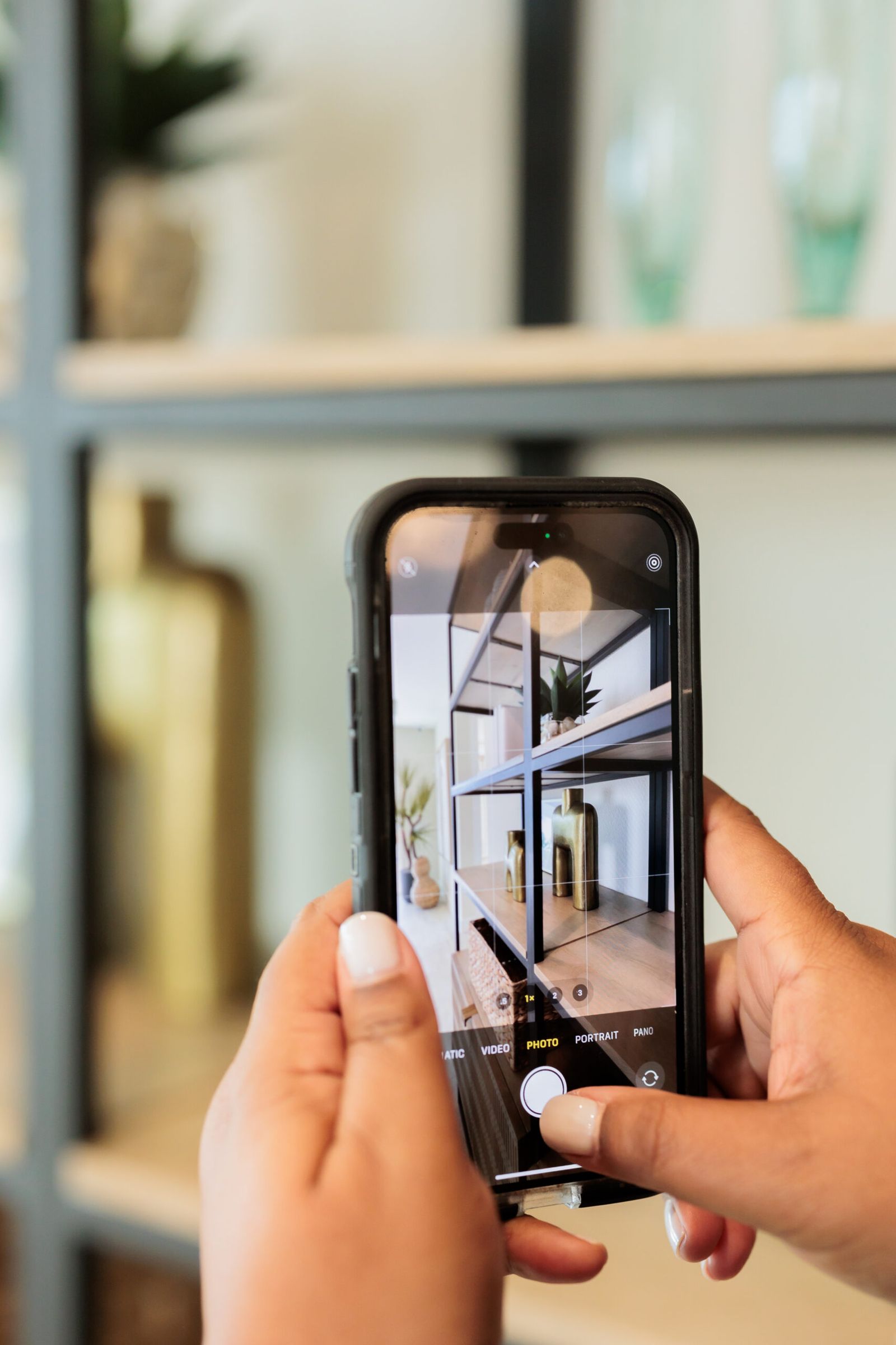 two hands holding up an iPhone while taking photos of home decor items