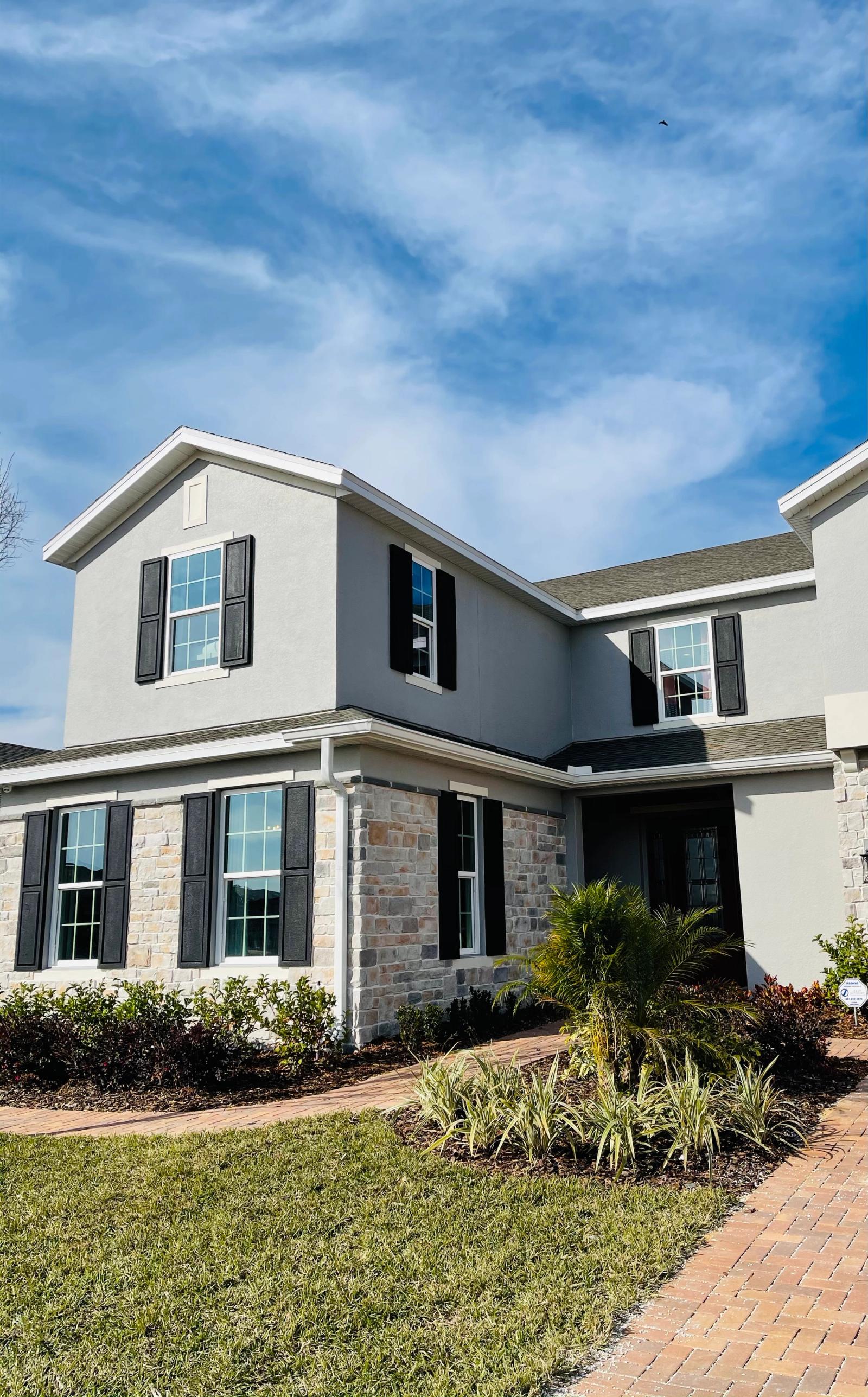 Two-story new construction home with stone accents and paver driveway in a Minneola, Florida master-planned community