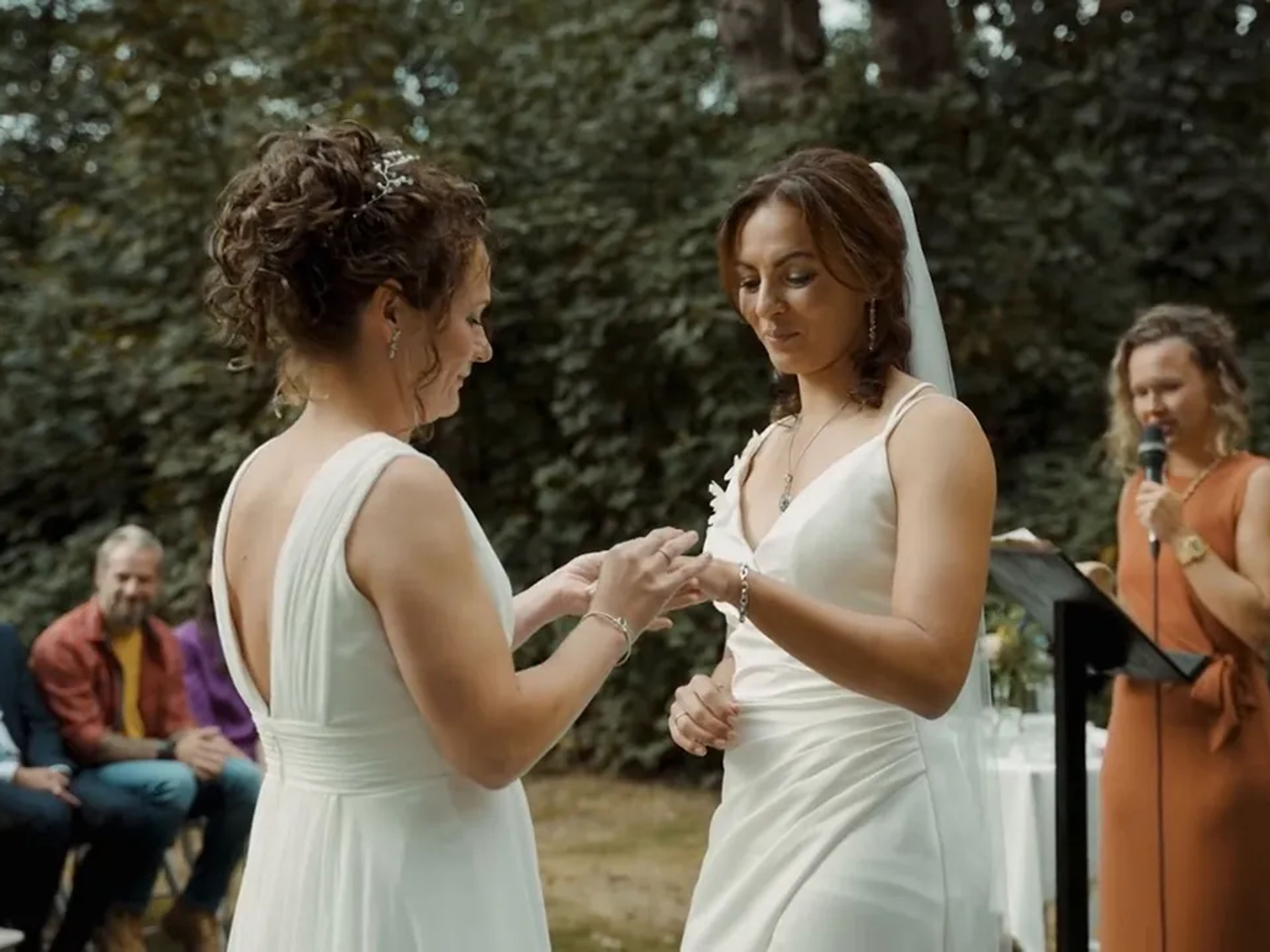 Two brides exchanging rings in front of their guests