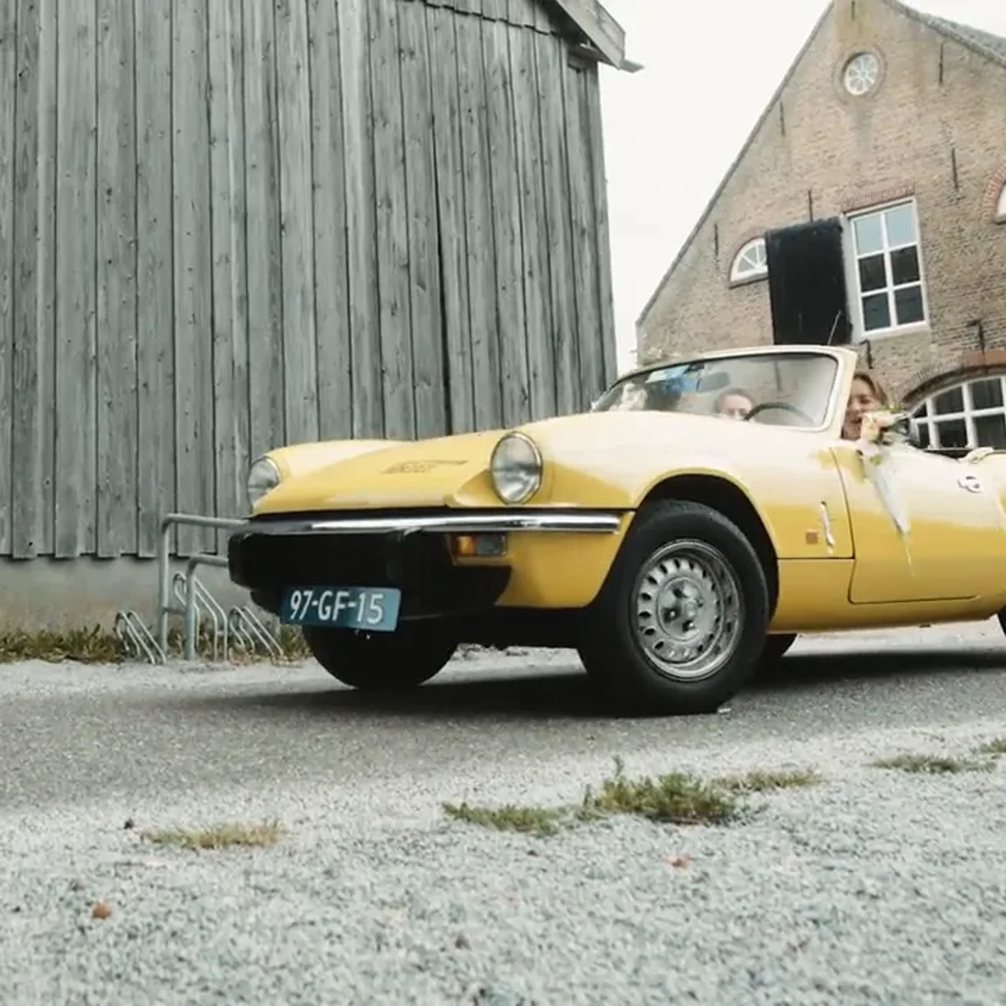 Yellow wedding car by a barn