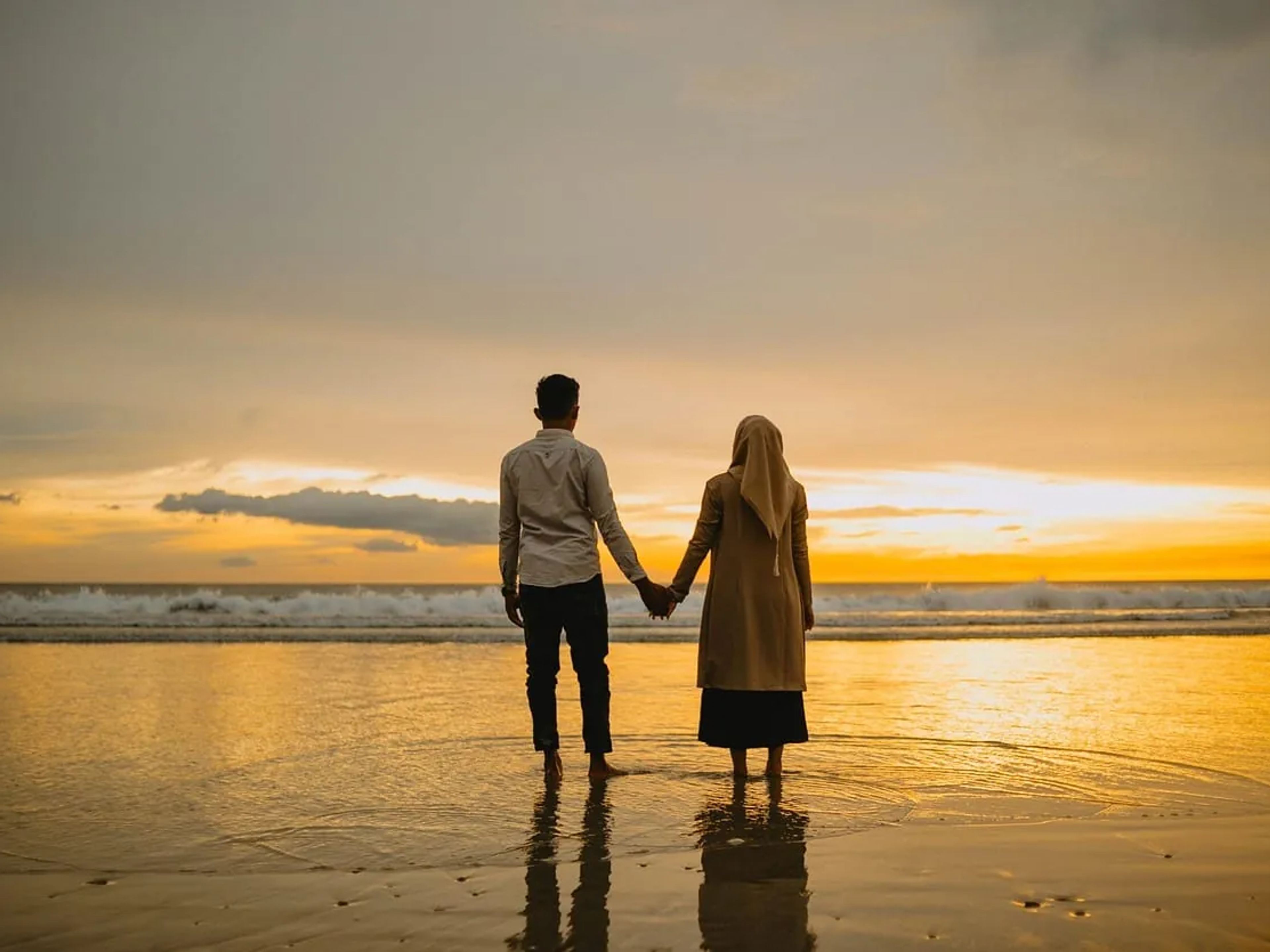 Couple hand in hand at sunset by the sea