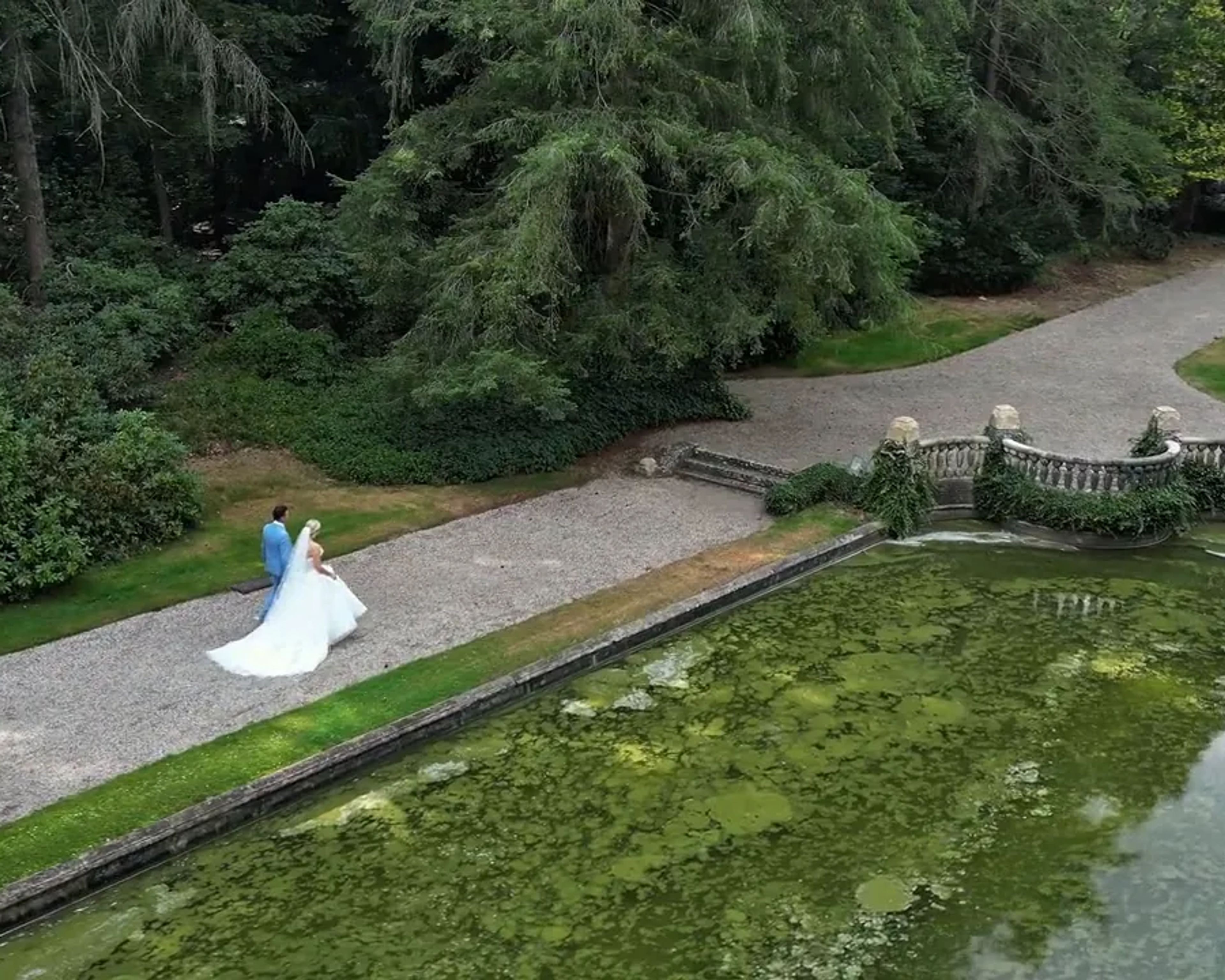 Aerial view of a couple on the path along a pond on an estate