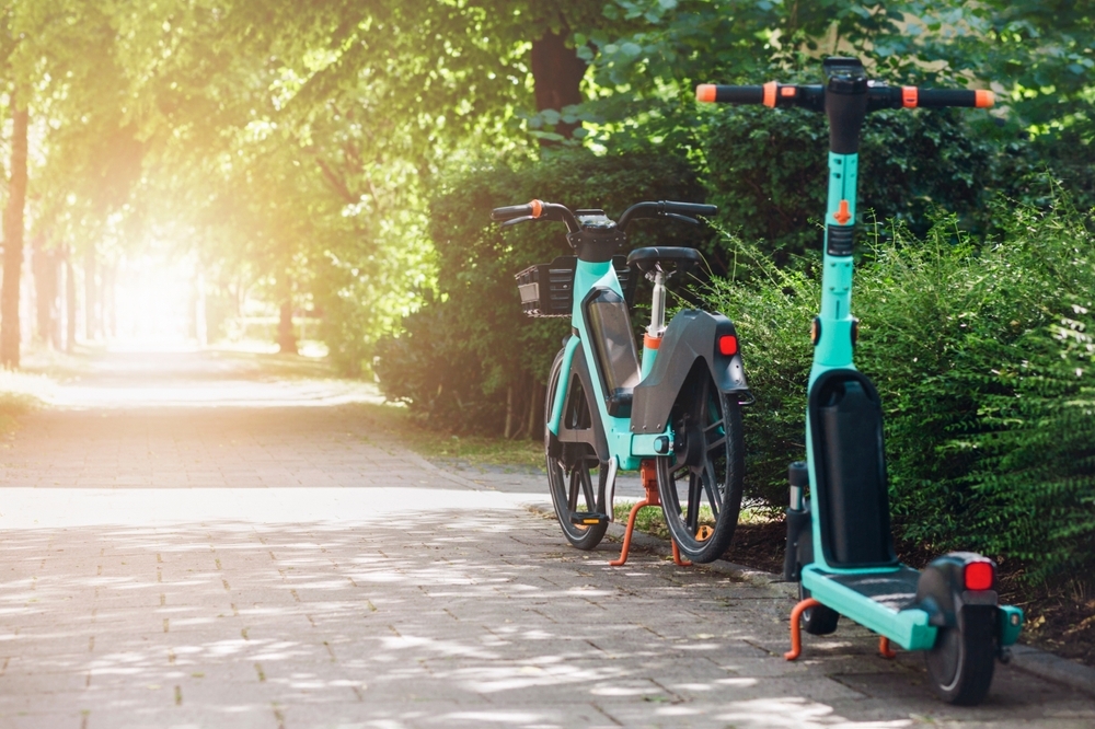 Image Parked rental e-bike and electric scooter on a tree-lined path, highlighting e-bike crash injury and traumatic brain injury risks in New Jersey