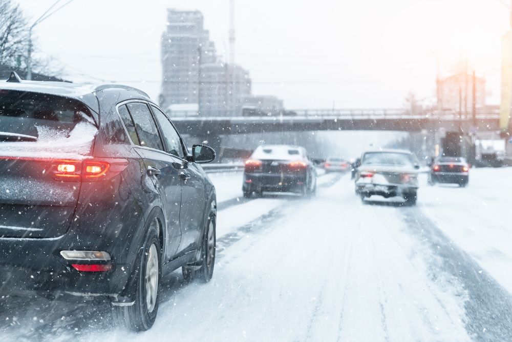 Car driving cautiously on a snow-covered New Jersey highway during winter weather and heavy traffic