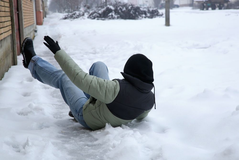Person falling on icy New Jersey sidewalk after snowstorm, illustrating winter slip and fall injuries that may lead to personal injury claims.