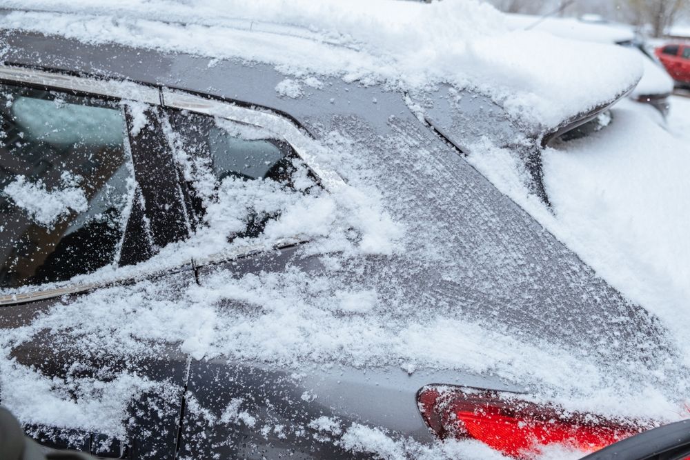 Snow and ice covering the roof of a car showing risk under New Jersey snow removal laws if ice flies off and causes a crash