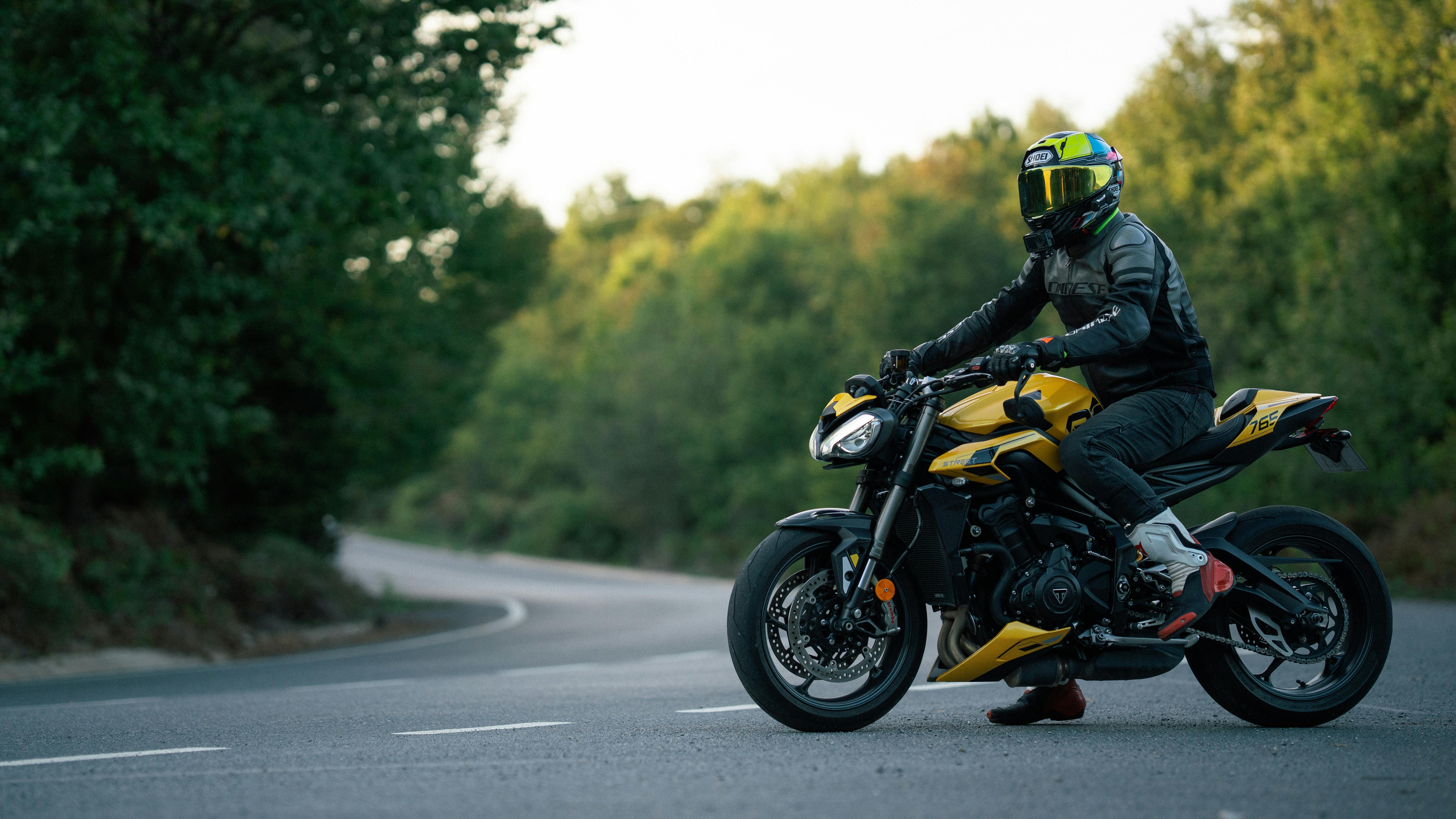 Motorcyclist riding a yellow motorcycle on a winding road, highlighting motorcycle accident risks in New Jersey.
