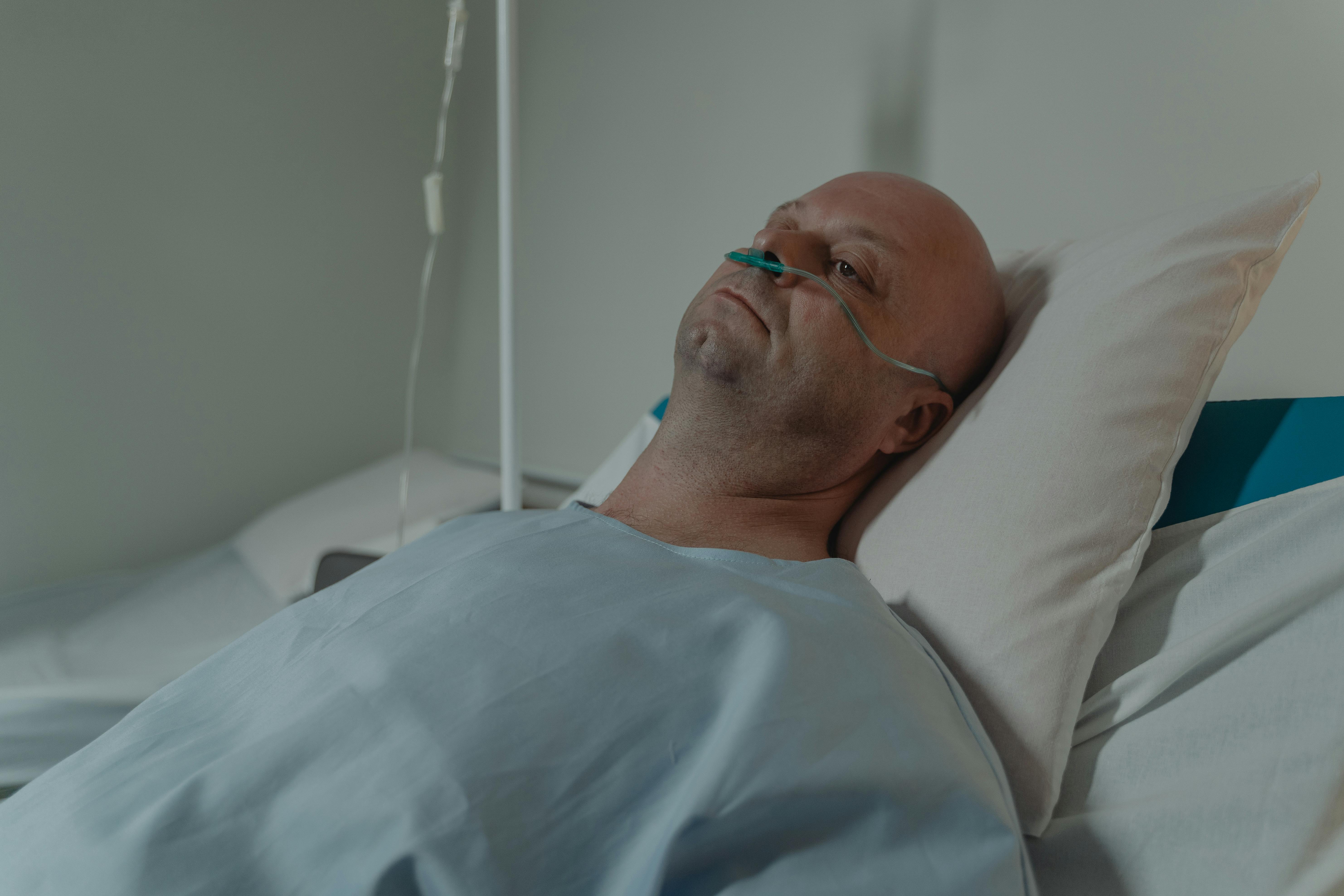 Patient lying in hospital bed with oxygen support reflecting the emotional impact of a delayed cancer diagnosis caused by screening errors