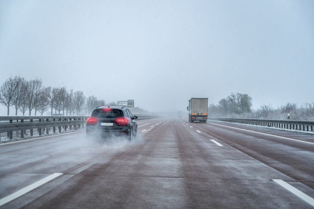 A car driving on a slushy and wet New Jersey highway during hazardous winter weather conditions.