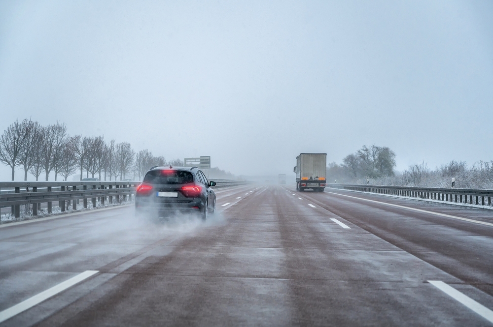 Image A car driving on a slushy and wet New Jersey highway during hazardous winter weather conditions.