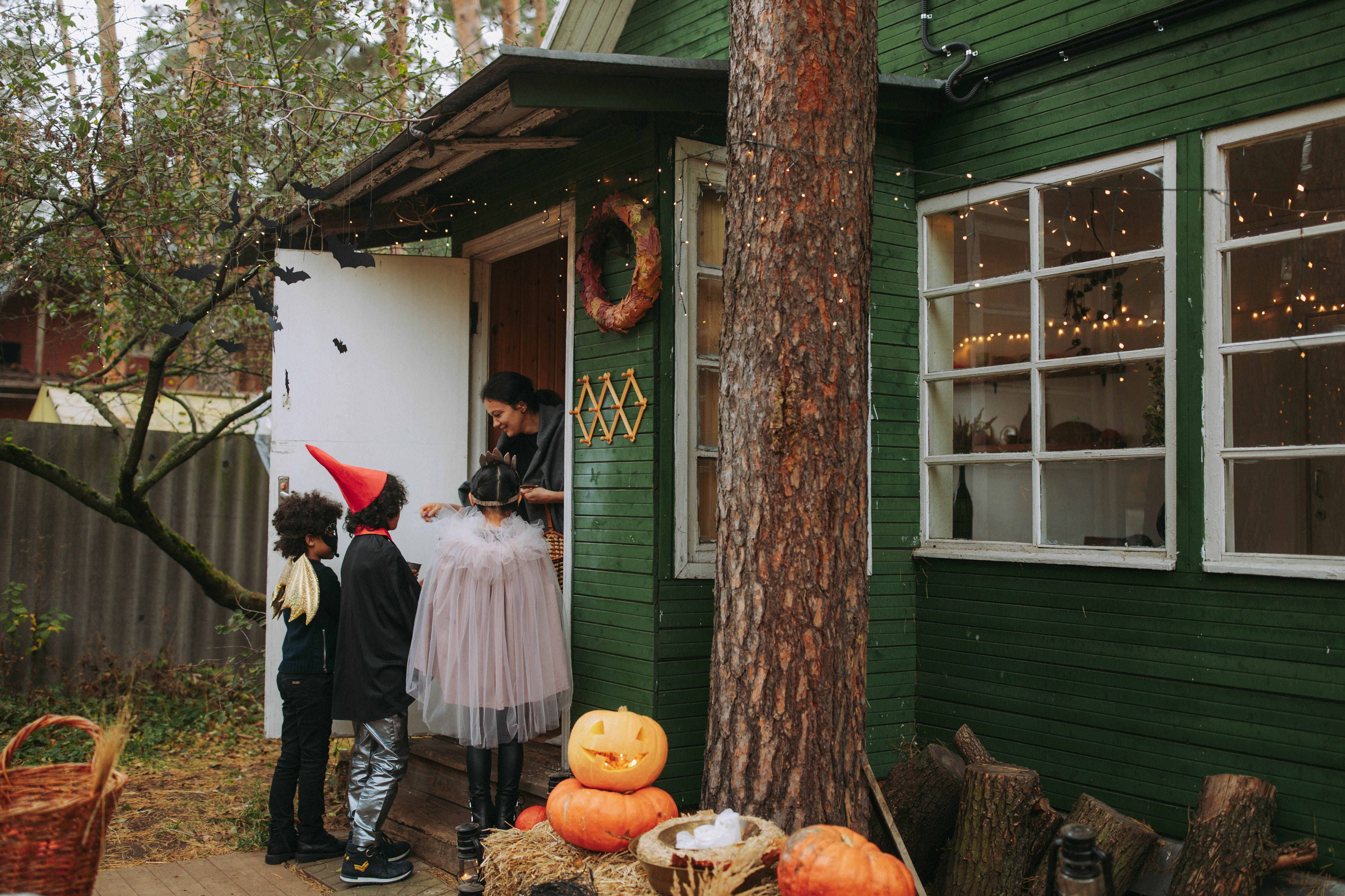 Image Halloween pedestrian safety tips keep trick-or-treaters safe as costumed kids collect candy at a decorated porch with jack-o'-lanterns