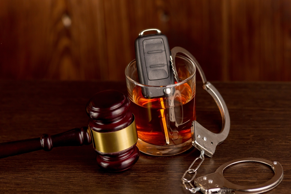 Image Car keys sitting in a glass of alcohol next to a gavel and handcuffs, symbolizing DUI arrests and legal consequences on Thanksgiving Eve in New Jersey.