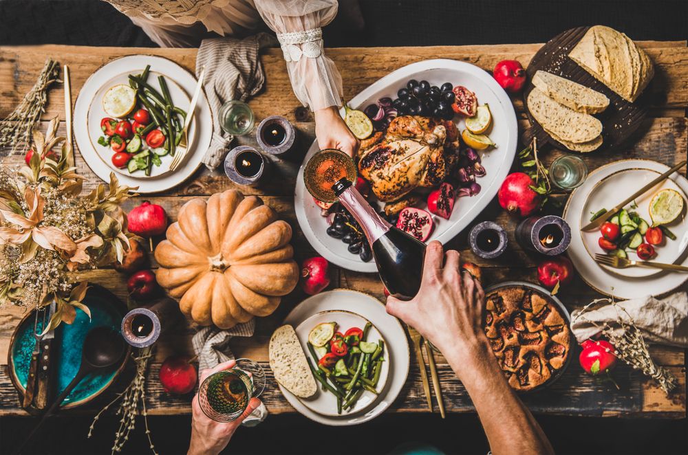 Overhead view of a Thanksgiving dinner table with guests pouring wine, highlighting holiday gatherings where alcohol is served before potential drunk driving accidents.