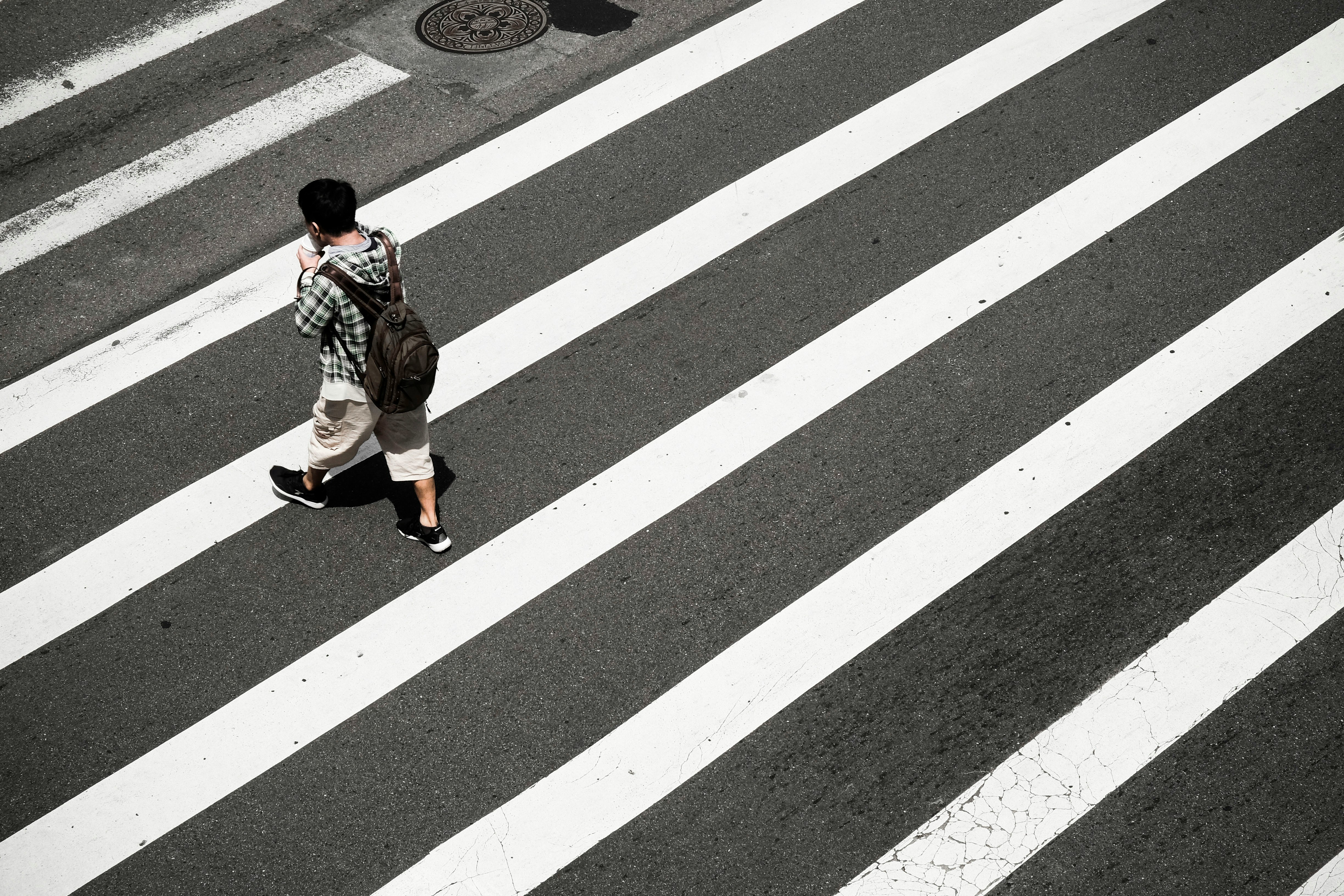 Image Pedestrian with a backpack walking across a city crosswalk, illustrating the risk of Newark pedestrian accidents.