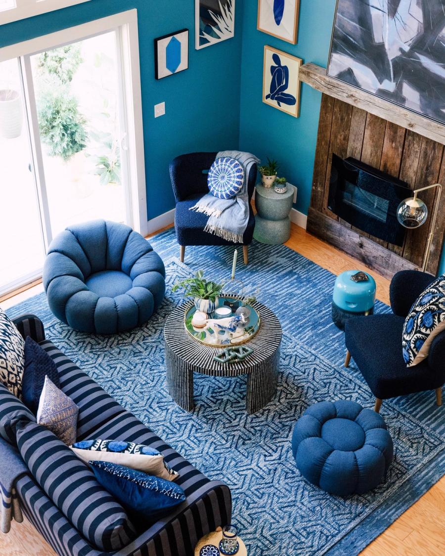 Overhead view of a blue living room with HomeGoods poufs, patterned rug and round coffee table, styled for BuzzFeed by photographer Taylor Miller.
