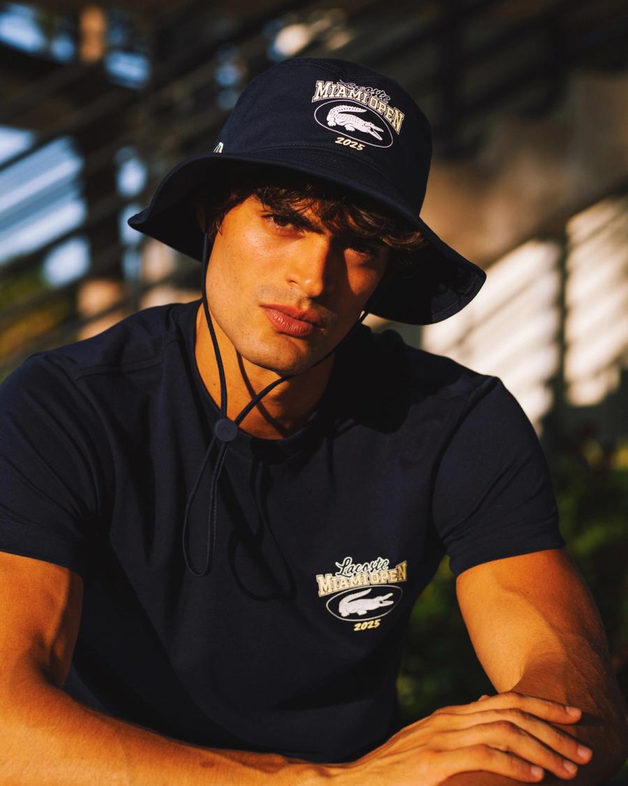 Iago Botelho in a navy Lacoste Miami Open 2025 bucket hat and graphic tee, photographed for Lacoste by Taylor Miller.