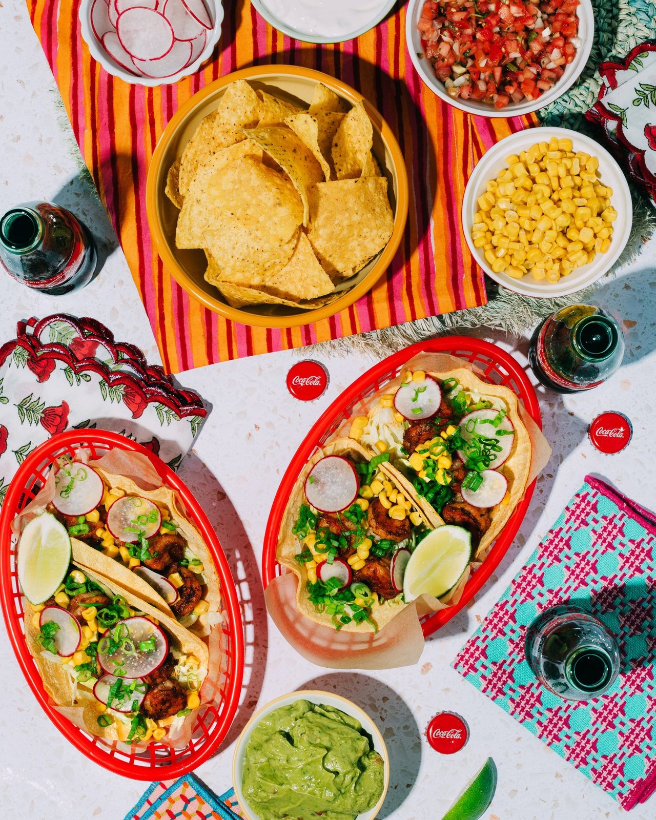 Overhead taco spread with street tacos, tortilla chips, guacamole and glass Coca-Cola bottles, for Coca-Cola and BuzzFeed by Taylor Miller.