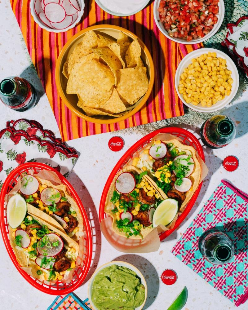Overhead taco spread with street tacos, tortilla chips, guacamole and glass Coca-Cola bottles, for Coca-Cola and BuzzFeed by Taylor Miller.