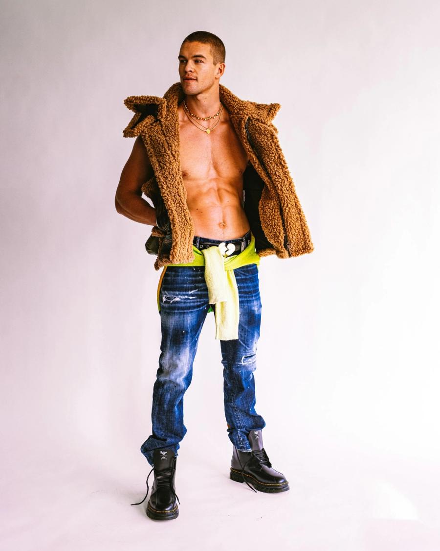 Mitchell Slaggert in a tan shearling jacket over a bare chest, distressed jeans and a neon sweater tied at the waist, for Numéro Netherlands by Taylor Miller.