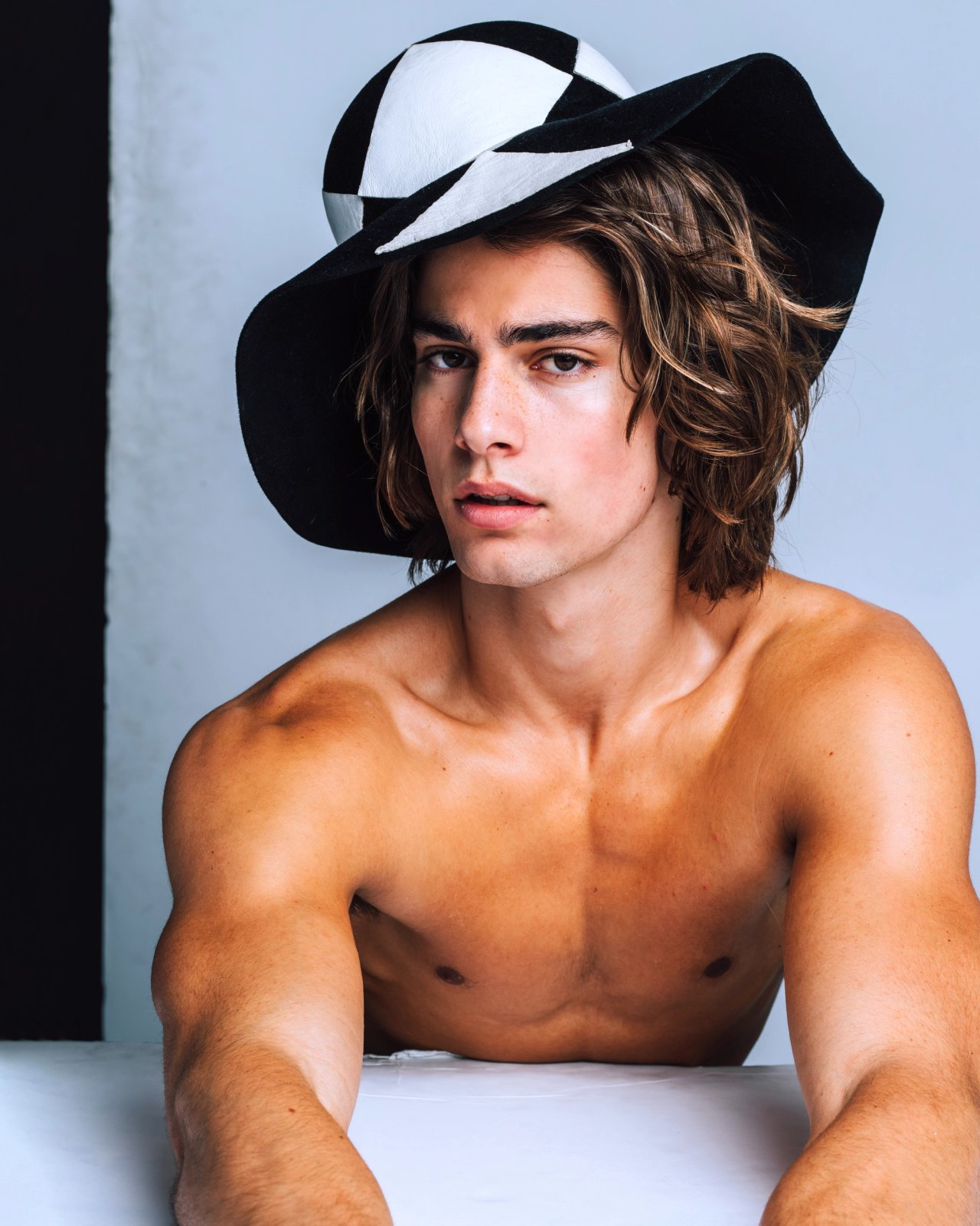 Model Corrado Martini, wearing a black and white hat, photographed for L'Officiel Hommes Poland shot by photographer Taylor Miller.