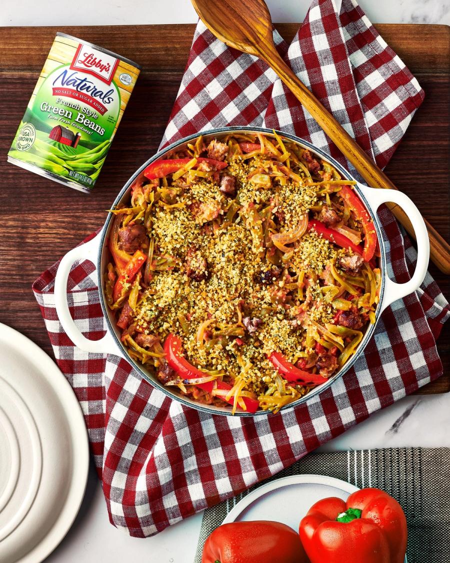 Green bean noodle stir-fry topped with seeds in a white pot beside a Libby's Naturals can and fresh tomatoes, for BuzzFeed by Taylor Miller.