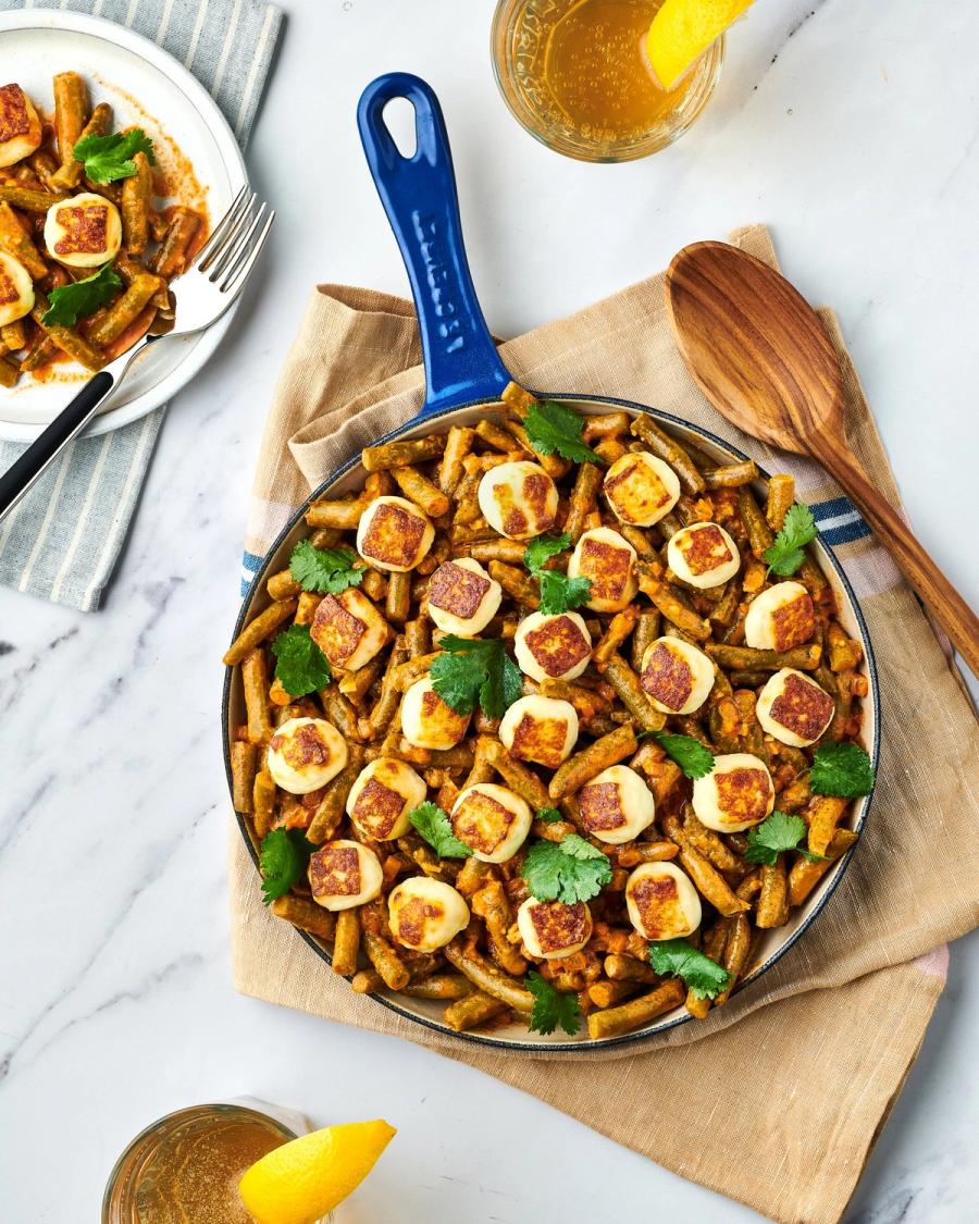 Blue skillet of green beans with seared halloumi and cilantro, plated portion and lemon nearby, for Libby's and BuzzFeed by Taylor Miller.