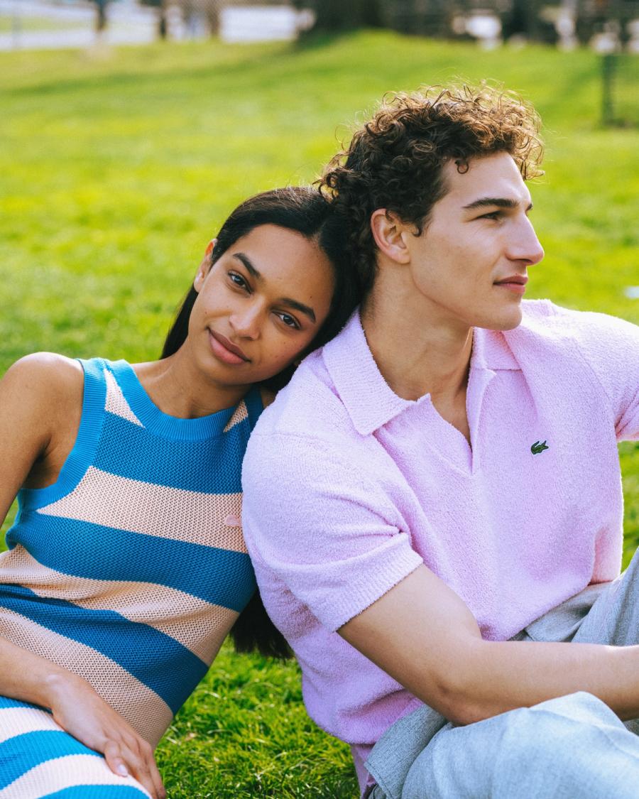 Franciele Santos in a blue striped knit and Sacha Bilal in a pink Lacoste polo on grass, for the Lacoste NYC 2026 campaign by Taylor Miller.