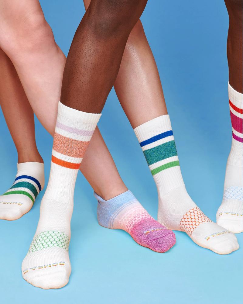 Close-up of legs in white Bombas crew and ankle socks with assorted Pride stripes, photographed for Bombas Pride 2024 by Taylor Miller.