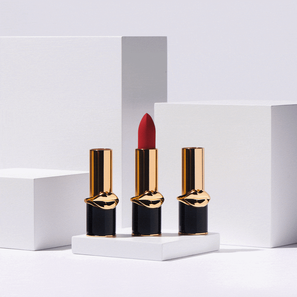 Stop motion of three lipstick bullets in black and gold tubes with a gold lips emblem, arranged on white pedestals, photographed by Taylor Miller.