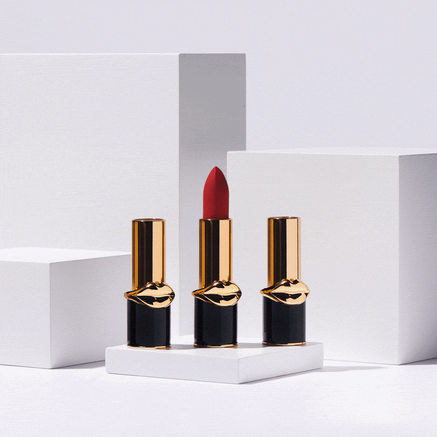 Stop motion of three lipstick bullets in black and gold tubes with a gold lips emblem, arranged on white pedestals, photographed by Taylor Miller.