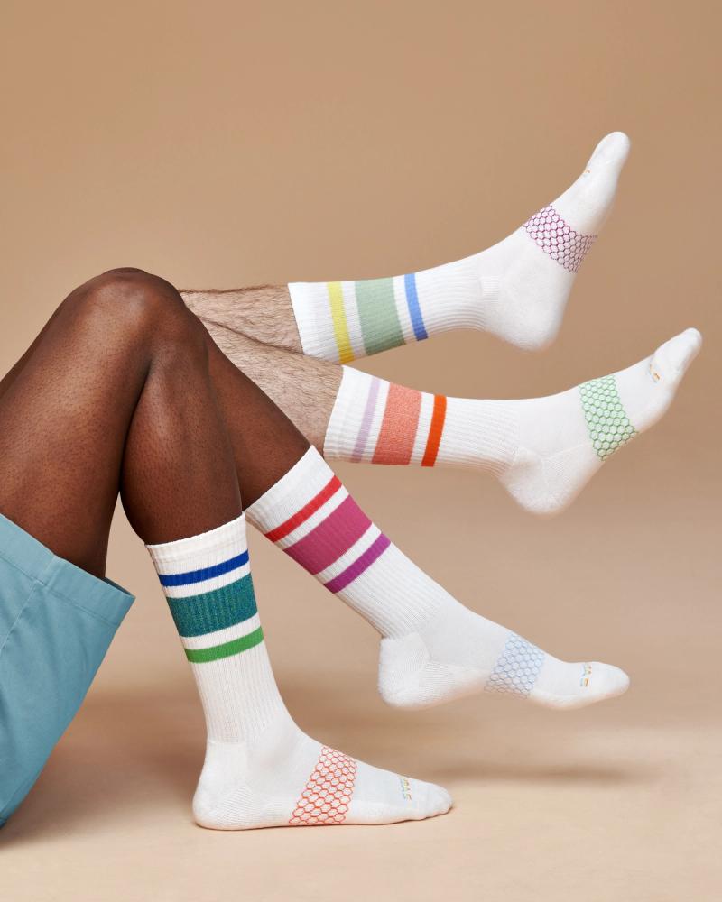 White Bombas crew socks with multicolored Pride stripes worn on several legs, photographed for the Bombas Pride 2024 campaign by Taylor Miller.