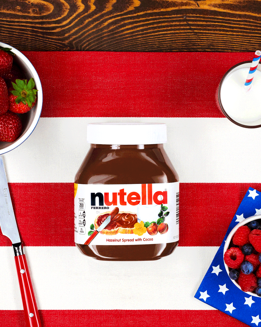 Patriotic breakfast flat lay with a jar of Nutella, waffles and bowls of berries on a red and white striped runner, photographed by Taylor Miller.