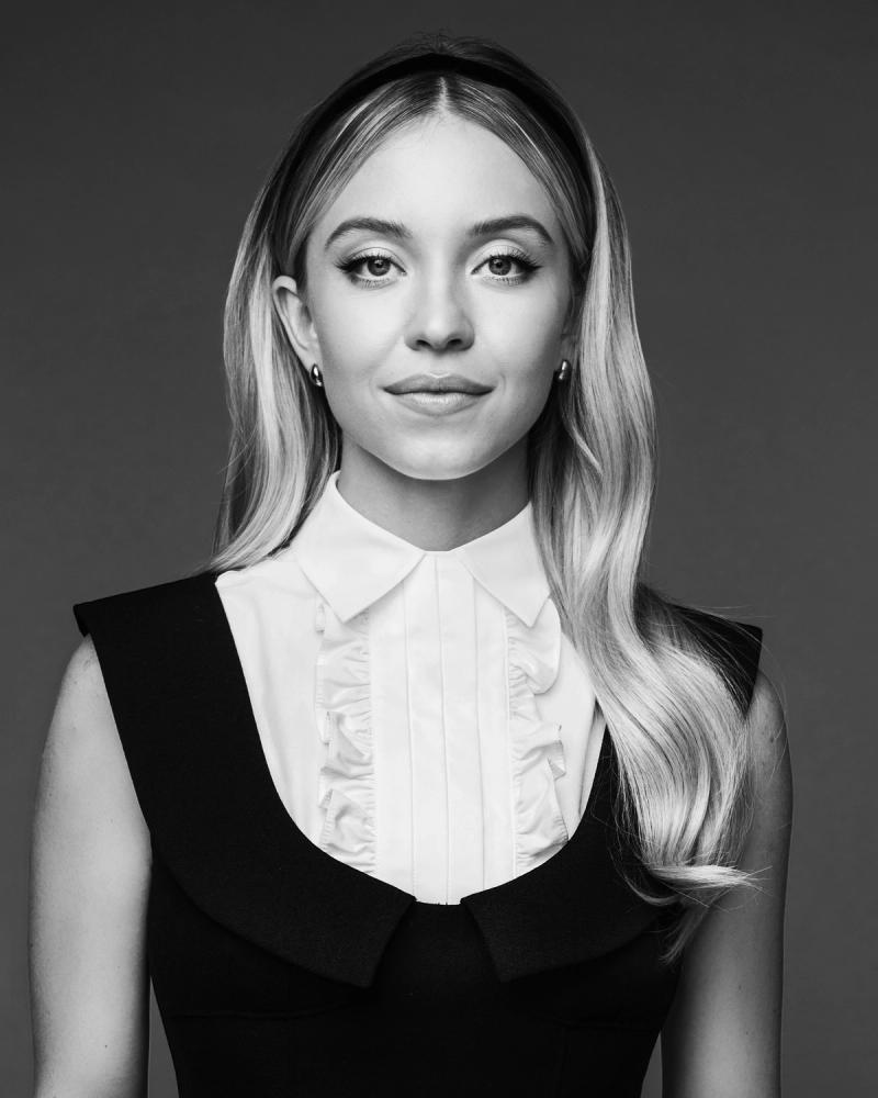 Actress Sydney Sweeney wears a black dress, looking straight to the camera, photographed for BuzzFeed in New York City by celebrity and fashion photographer Taylor Miller.