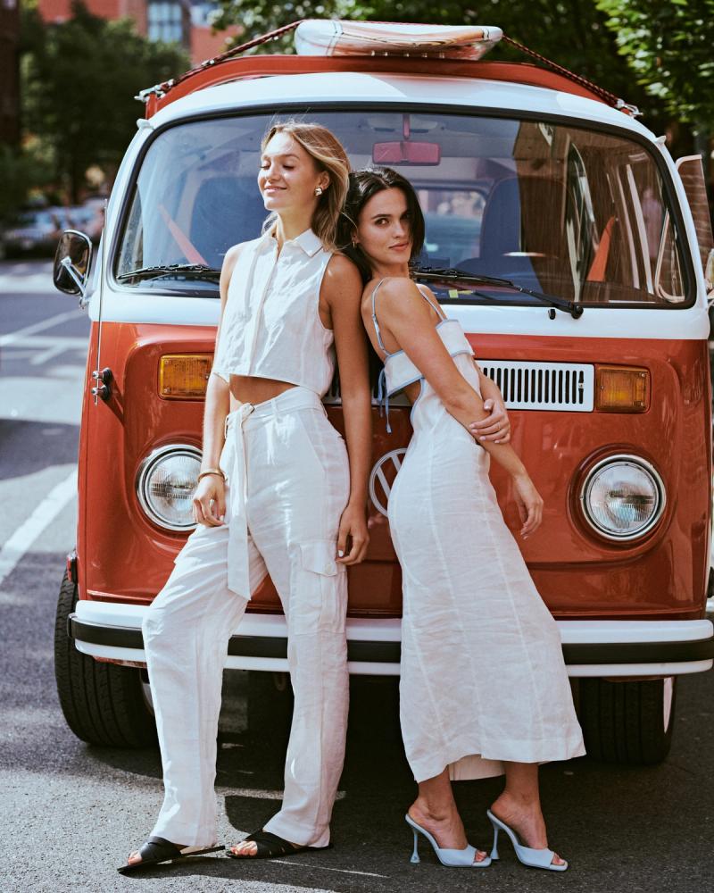 Mary Holland Nader and Julia Lisboa in white linen looks leaning back to back against a vintage red camper van for the ESYA editorial campaign, photographed by Taylor Miller.
