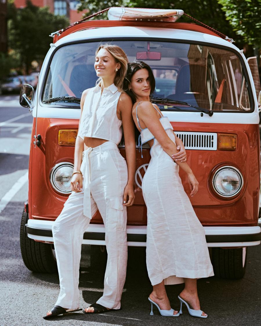 Mary Holland Nader and Julia Lisboa in white linen looks leaning back to back against a vintage red camper van for the ESYA editorial campaign, photographed by Taylor Miller.