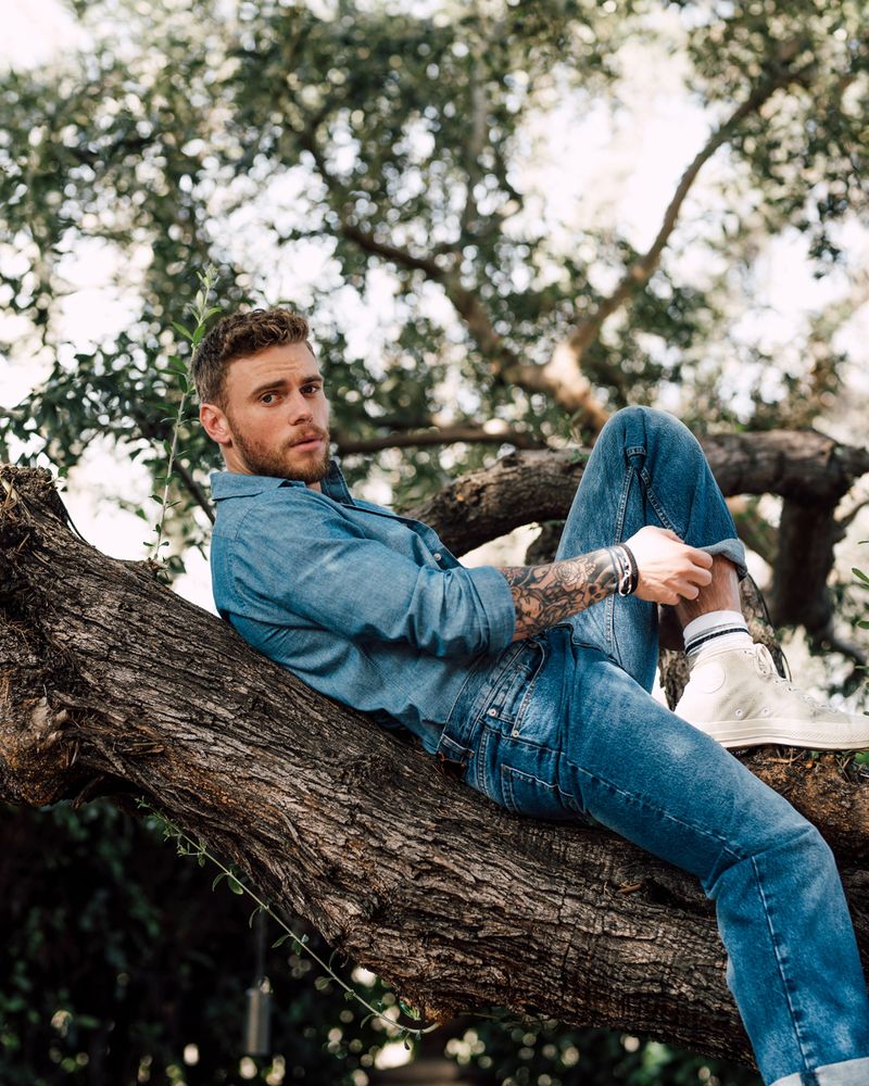 Former Olympic skier Gus Kenworthy, wearing a full denim outfit and laying on a tree brranch, photographed in Los Angeles by fashion and celebrity photographer Taylor Miller who is located in Brooklyn, NY. 