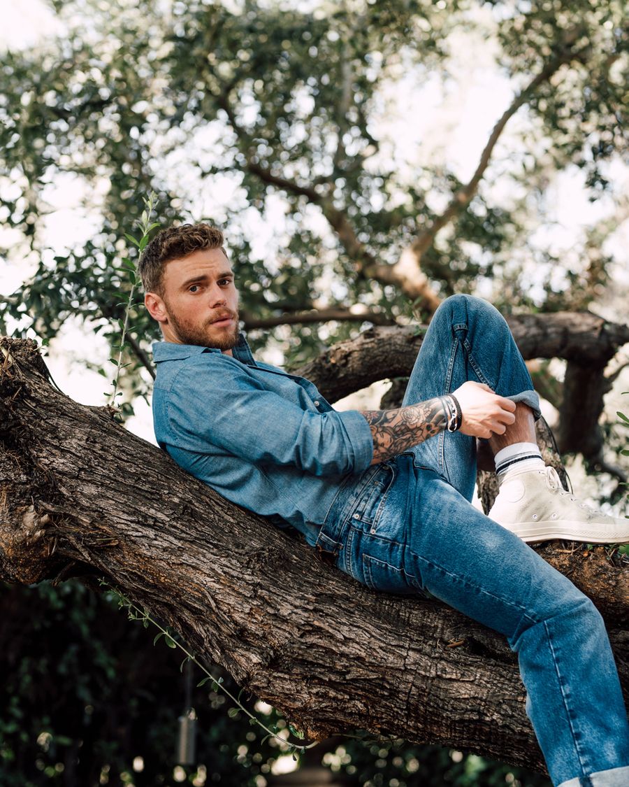 Former Olympic skier Gus Kenworthy, wearing a full denim outfit and laying on a tree brranch, photographed in Los Angeles by fashion and celebrity photographer Taylor Miller who is located in Brooklyn, NY. 