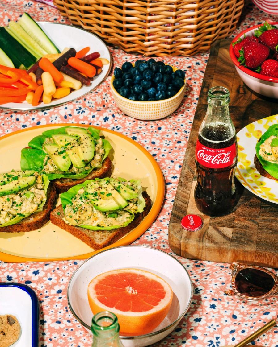 Brunch table of avocado toast, fresh berries and grapefruit beside a glass bottle of Coca-Cola, photographed for Coca-Cola and BuzzFeed by Taylor Miller.