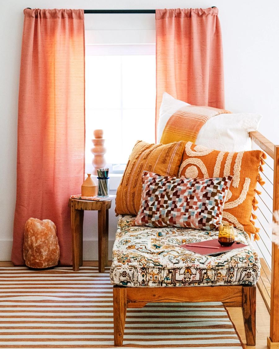 Cozy corner bench layered with terracotta HomeGoods pillows and curtains beside a salt lamp, styled for BuzzFeed by photographer Taylor Miller.