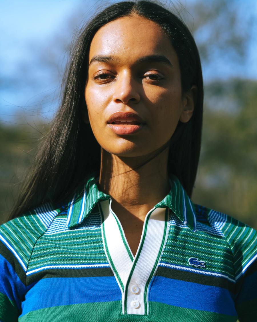 Outdoor portrait of Franciele Santos in a green and blue striped Lacoste polo for the Lacoste NYC 2026 campaign, photographed by Taylor Miller.