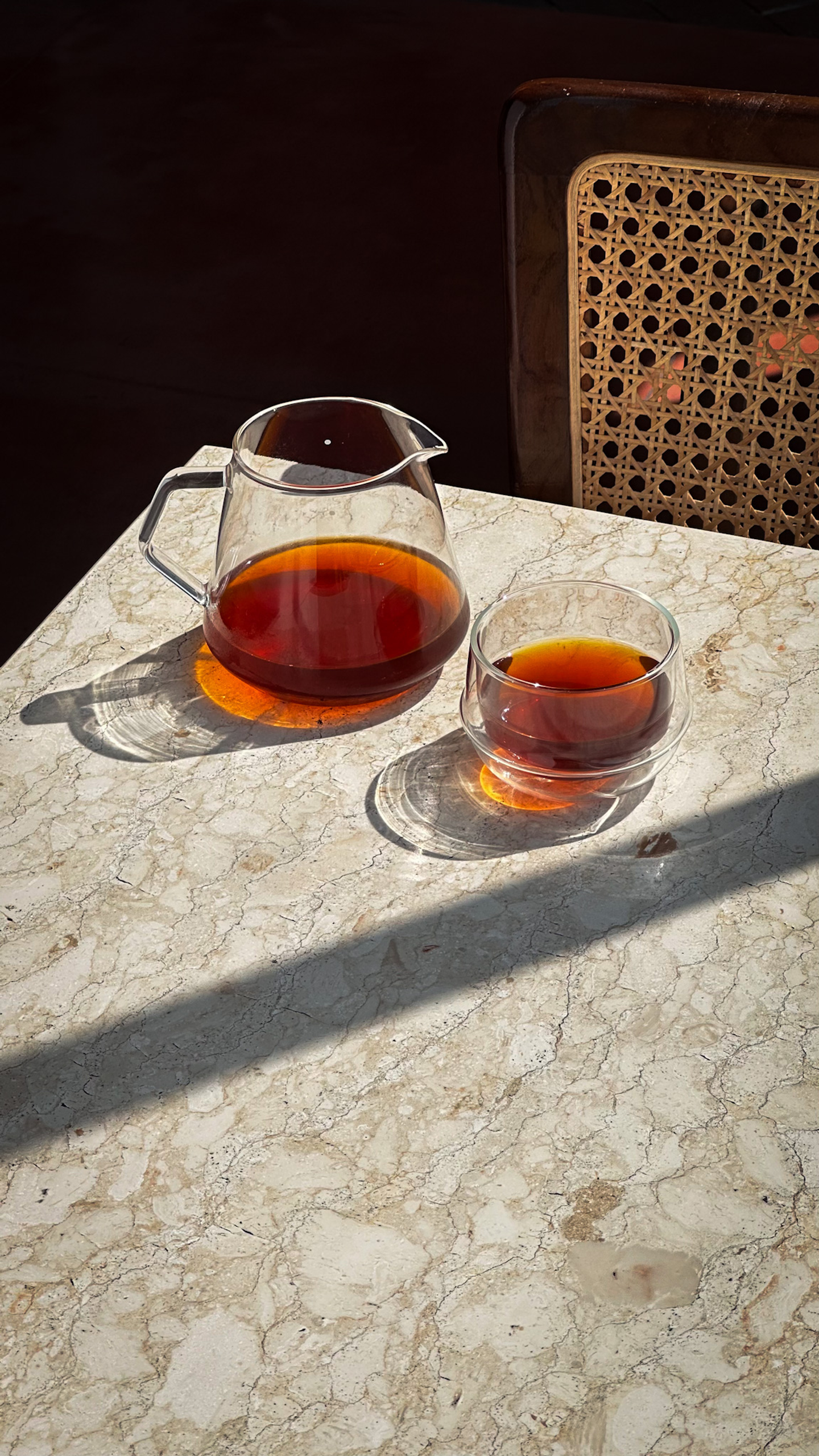 Glass carafe and cup with filter coffee on marble table, reflecting warm, inviting atmosphere and branding details for Sunday Kitchen, Brazilian restaurant in Canggu Bali