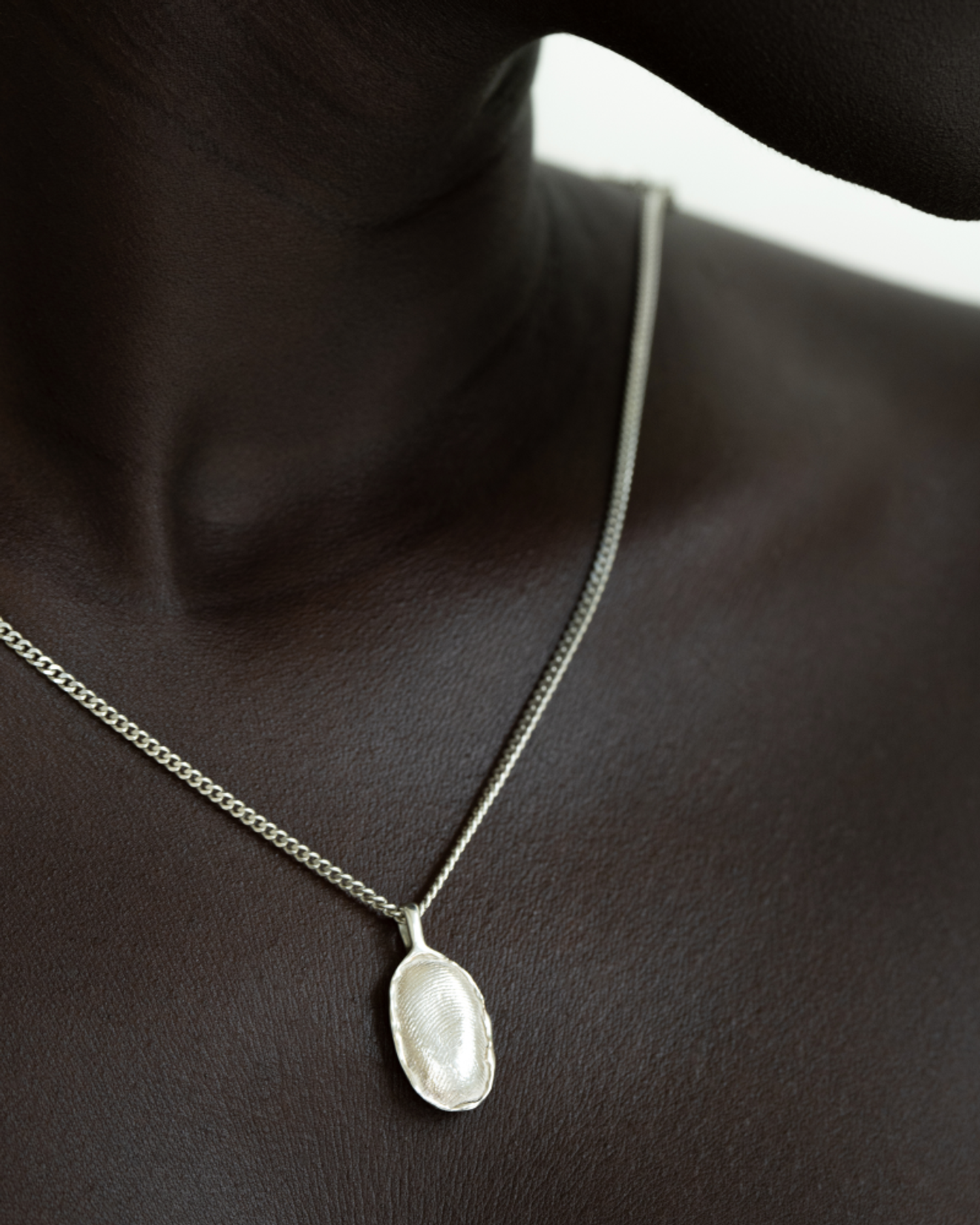 Close‑up of OMOI Jewelry silver Forever Pendant showing fingerprint pattern on oval charm and curb chain, photographed for e‑commerce and brand identity by Eeze Studio