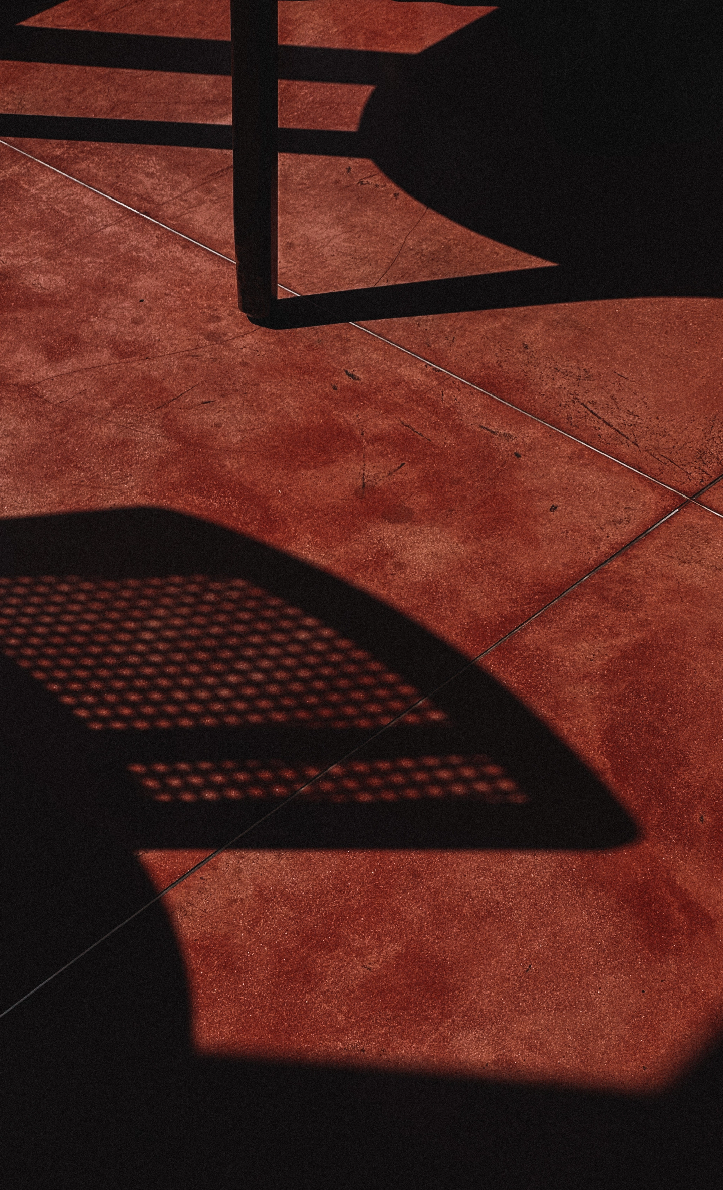 Sunday Kitchen Sunlit Flooring – Restaurant Design Detail in Canggu Geometric shadow patterns on red stone flooring in Sunday Kitchen, emphasizing restaurant interior and branding design for Brazilian cuisine in Canggu Bali