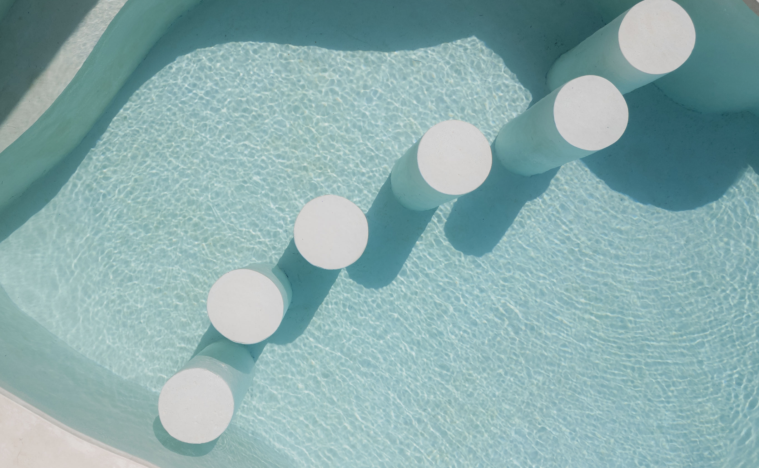 House of Creations Bali – Designer Pool Steps and Water Detail Overhead view of geometric white steps in calm blue pool, highlighting luxury villa amenities and architectural branding in House of Creations Bali