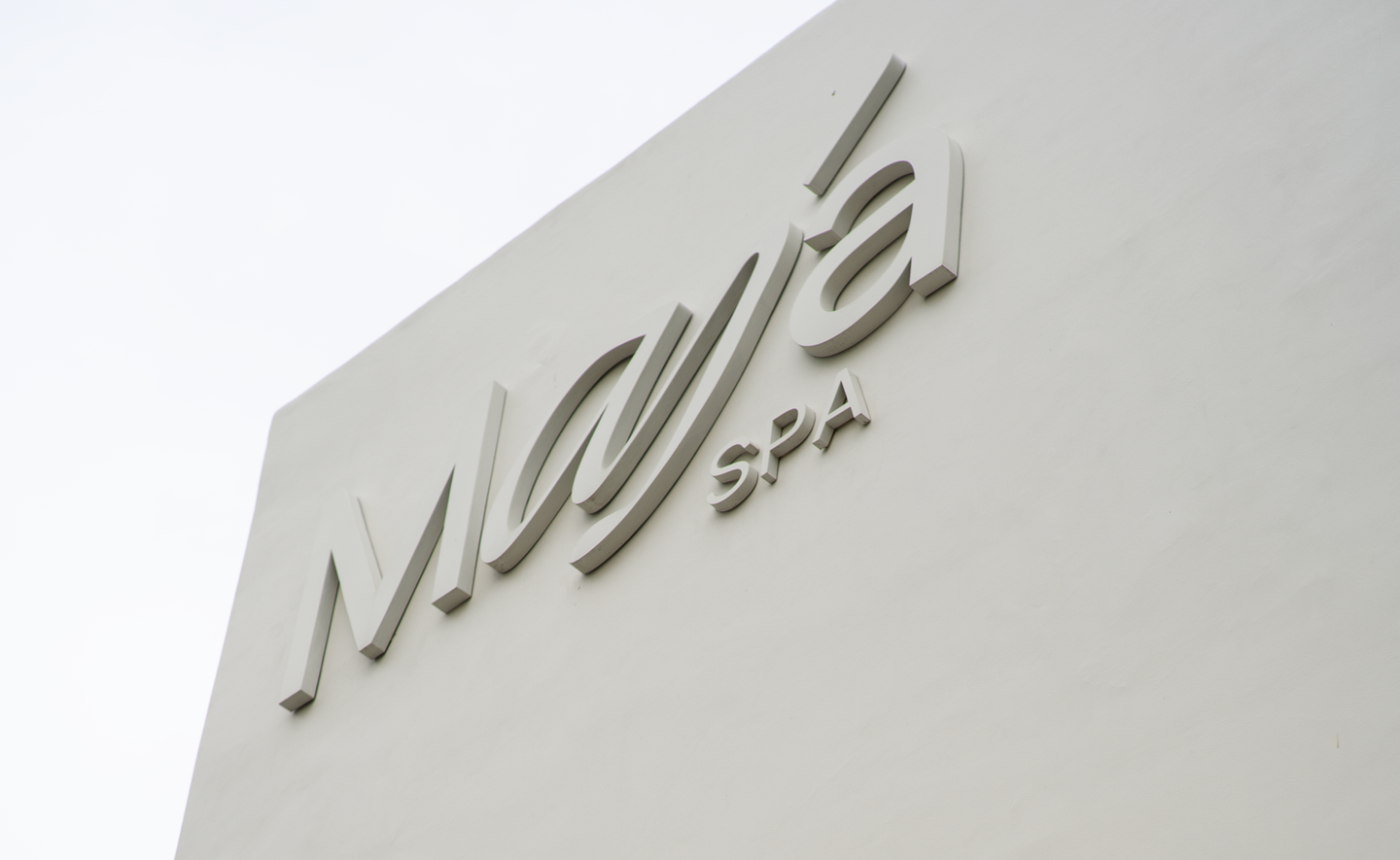 MAJA Bali Spa Exterior Signage – Boutique Hotel Branding Design Minimalist embossed MAJA Spa logo on smooth white exterior wall, showcasing boutique hotel and spa branding in Bali by Eeze Studio