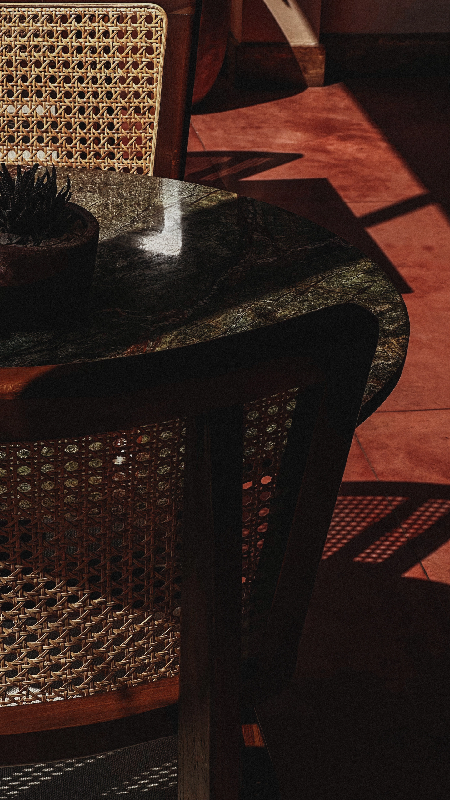 Detail of woven chair, marble table, and shadows in Sunday Kitchen interior, showcasing branding design and relaxed atmosphere for Brazilian restaurant in Canggu Bali