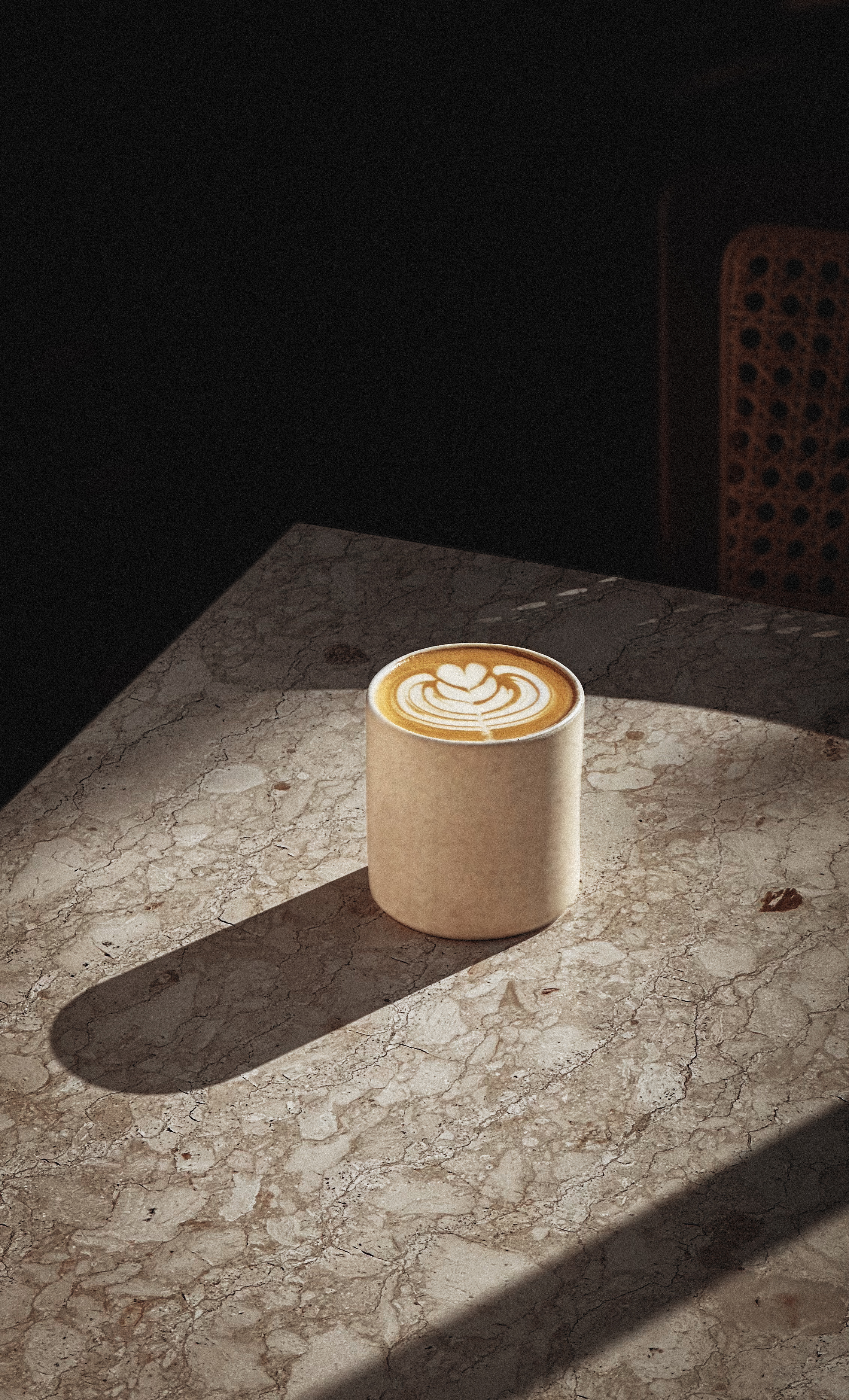 Sunday Kitchen Latte Art – Brazilian Eatery Coffee Experience in Bali Artisan latte with symmetrical foam art served in ceramic mug on marble table, highlighting Brazilian coffee experience and ambiance in Sunday Kitchen, Canggu Bali