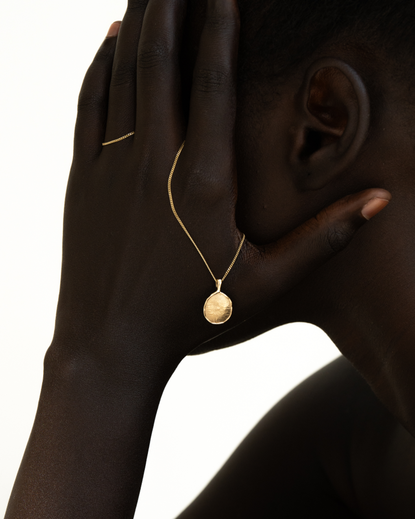Side profile of model with hand to ear wearing OMOI Jewelry gold Forever Pendant on delicate chain, photographed for brand identity and Shopify site by Eeze Studio